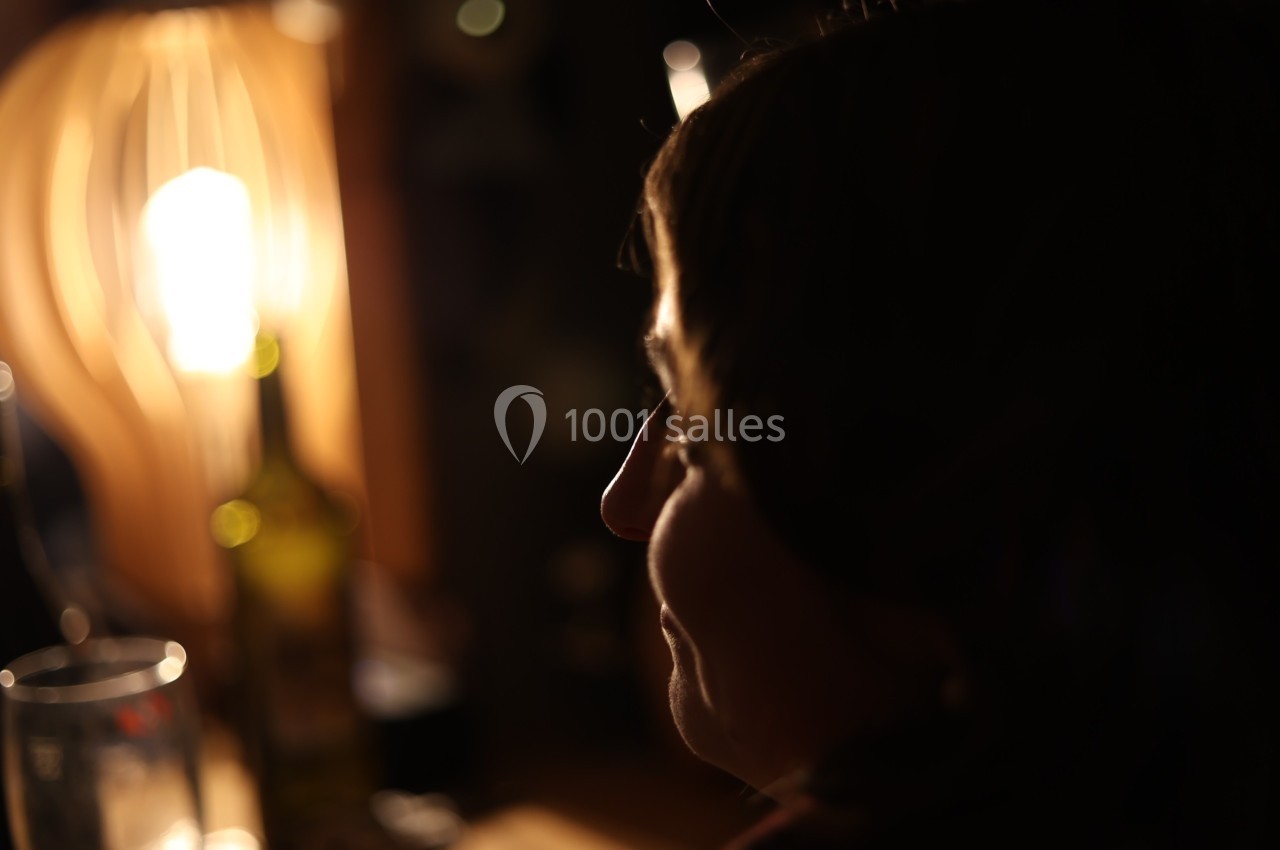 Femme de profil dans une ambiance tamisée, éclairée par une lampe chaude en arrière-plan.