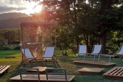 Chambre lumineuse avec lit double, télévision murale, bureau en bois, deux chaises et rideaux blancs filtrant la lumière.