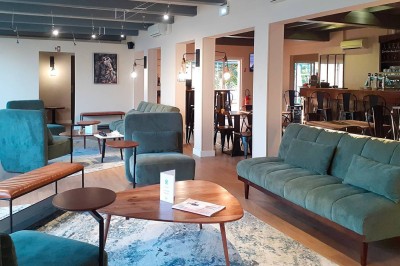 Chambre lumineuse avec lit double, télévision murale, bureau en bois, deux chaises et rideaux blancs filtrant la lumière.