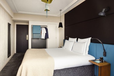 Miniature Location salle Paris 18 (Paris) - Terrass' Hotel #10 Chambre lumineuse avec un lit double, des murs sombres, une verrière, un fauteuil bleu et des rideaux blancs et bleus.