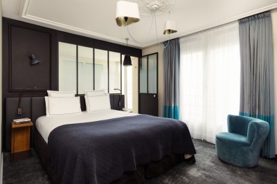 Miniature Location salle Paris 18 (Paris) - Terrass' Hotel #11 Chambre lumineuse avec un lit double, des murs sombres, une verrière, un fauteuil bleu et des rideaux blancs et bleus.