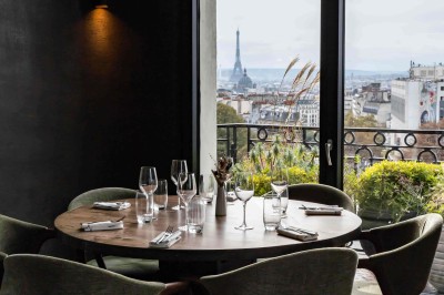 Miniature Location salle Paris 18 (Paris) - Terrass' Hotel #9 Chambre lumineuse avec un lit double, des murs sombres, une verrière, un fauteuil bleu et des rideaux blancs et bleus.