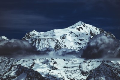 Chat tigré beige et brun bâillant, allongé sur un fauteuil bleu dans un intérieur lumineux.