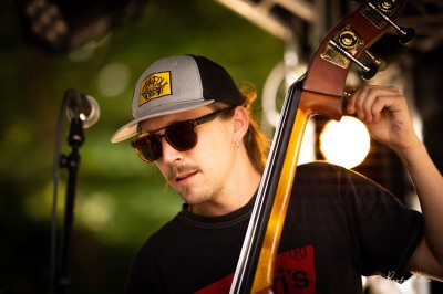 Chat tigré beige et brun bâillant, allongé sur un fauteuil bleu dans un intérieur lumineux.
