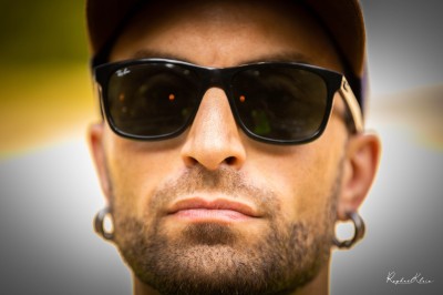 Chat tigré beige et brun bâillant, allongé sur un fauteuil bleu dans un intérieur lumineux.