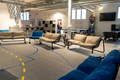 Espace de coworking moderne avec comptoir en bois, chaises hautes et mur décoré de fresques colorées.