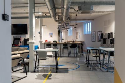 Espace de coworking moderne avec comptoir en bois, chaises hautes et mur décoré de fresques colorées.
