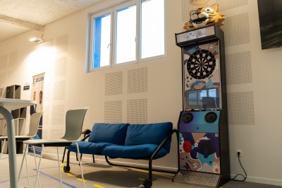 Espace de coworking moderne avec comptoir en bois, chaises hautes et mur décoré de fresques colorées.