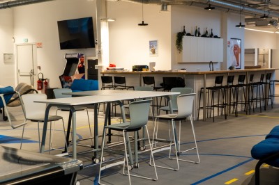 Espace de coworking moderne avec comptoir en bois, chaises hautes et mur décoré de fresques colorées.