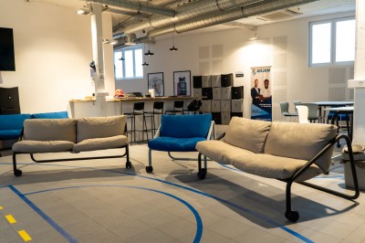 Espace de coworking moderne avec comptoir en bois, chaises hautes et mur décoré de fresques colorées.