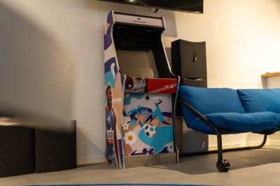 Espace de coworking moderne avec comptoir en bois, chaises hautes et mur décoré de fresques colorées.