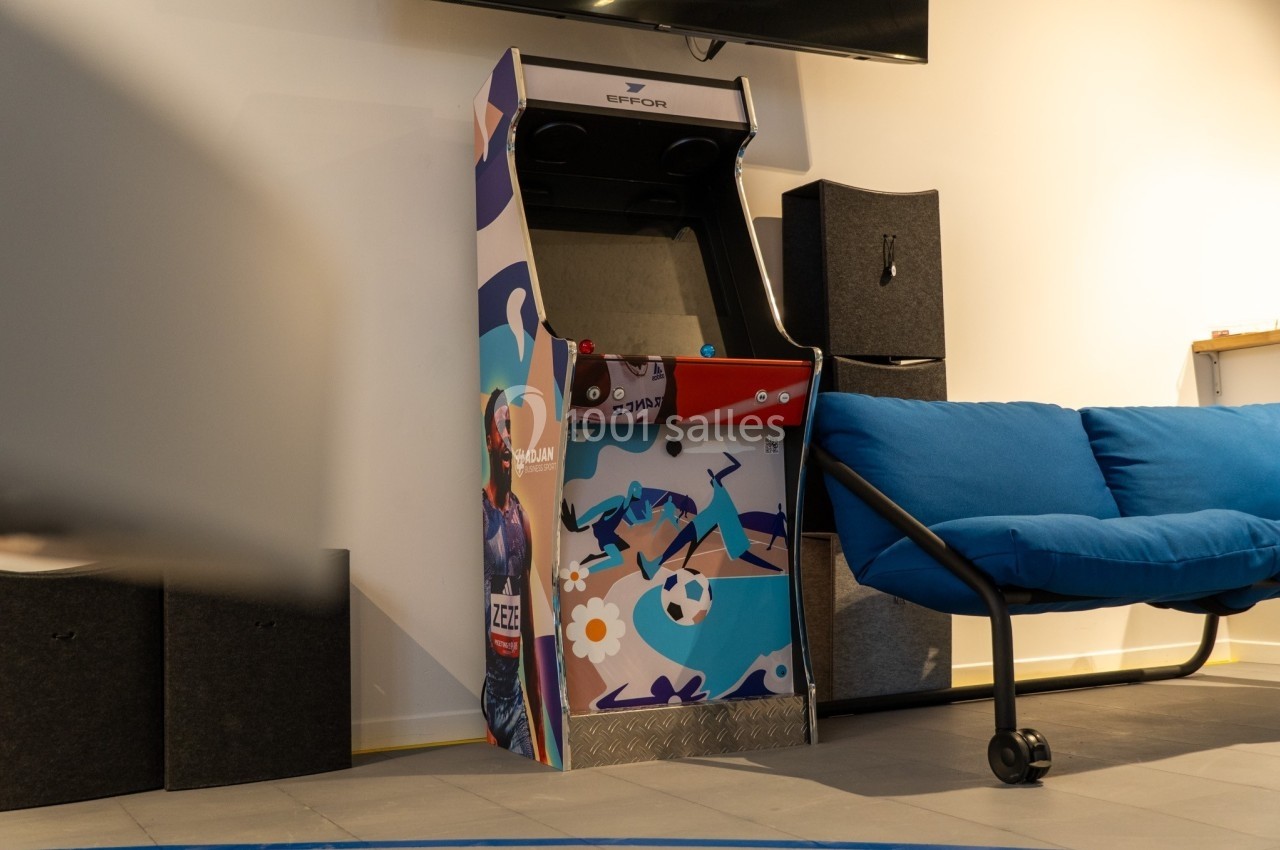 Borne d'arcade colorée placée près d'un canapé bleu dans un espace intérieur moderne.