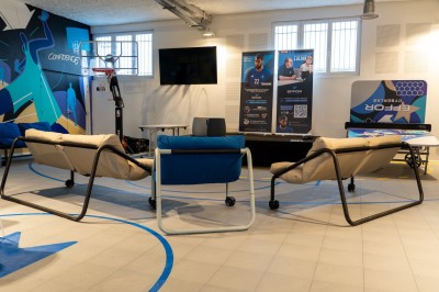 Espace de coworking moderne avec comptoir en bois, chaises hautes et mur décoré de fresques colorées.