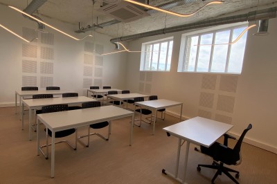 Lavabo double avec miroir, distributeur de papier et éclairage naturel dans une salle de bain aux murs blancs.