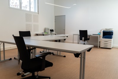 Lavabo double avec miroir, distributeur de papier et éclairage naturel dans une salle de bain aux murs blancs.