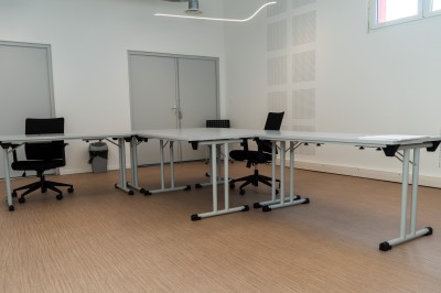 Lavabo double avec miroir, distributeur de papier et éclairage naturel dans une salle de bain aux murs blancs.