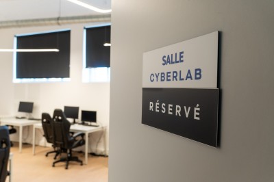 Lavabo double avec miroir, distributeur de papier et éclairage naturel dans une salle de bain aux murs blancs.