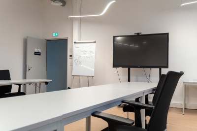 Lavabo double avec miroir, distributeur de papier et éclairage naturel dans une salle de bain aux murs blancs.