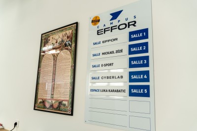 Lavabo double avec miroir, distributeur de papier et éclairage naturel dans une salle de bain aux murs blancs.