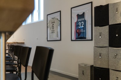 Lavabo double avec miroir, distributeur de papier et éclairage naturel dans une salle de bain aux murs blancs.