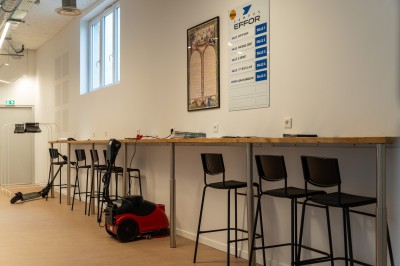 Lavabo double avec miroir, distributeur de papier et éclairage naturel dans une salle de bain aux murs blancs.