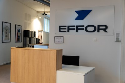 Lavabo double avec miroir, distributeur de papier et éclairage naturel dans une salle de bain aux murs blancs.