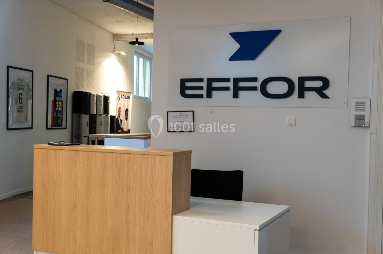 Bureau d'accueil avec un comptoir en bois, logo ’EFFOR’ sur le mur et cadres accrochés en arrière-plan.