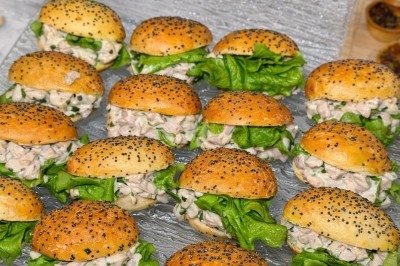 Petits pains garnis de salade verte et d'une préparation crémeuse, disposés sur un plateau en verre.