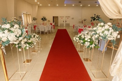 Miniature Location salle Fontenay-Trésigny (Seine-et-Marne) - L'Ecrin des Joyaux #3 Décor de mariage avec canapé blanc, table assortie et fleurs blanches et vertes sur une estrade ornée.