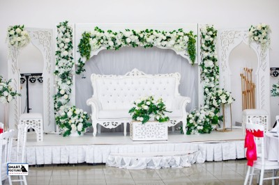 Miniature Location salle Fontenay-Trésigny (Seine-et-Marne) - L'Ecrin des Joyaux #8 Décor de mariage avec canapé blanc, table assortie et fleurs blanches et vertes sur une estrade ornée.