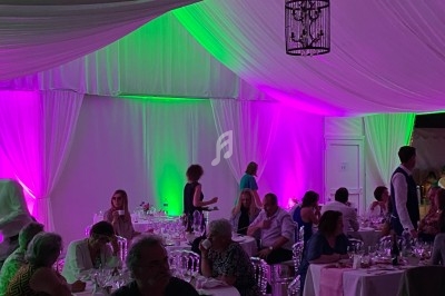 Salle de réception avec tables dressées et éclairage bleu projeté au plafond et sur le sol.