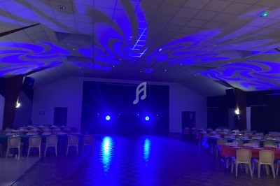Salle de réception avec tables dressées et éclairage bleu projeté au plafond et sur le sol.