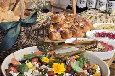 Table et deux chaises noires installées devant un mur beige avec une enseigne ’Nevian's Traiteur & Cave’.