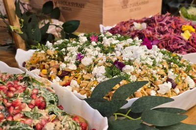 Table et deux chaises noires installées devant un mur beige avec une enseigne ’Nevian's Traiteur & Cave’.