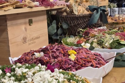 Table et deux chaises noires installées devant un mur beige avec une enseigne ’Nevian's Traiteur & Cave’.
