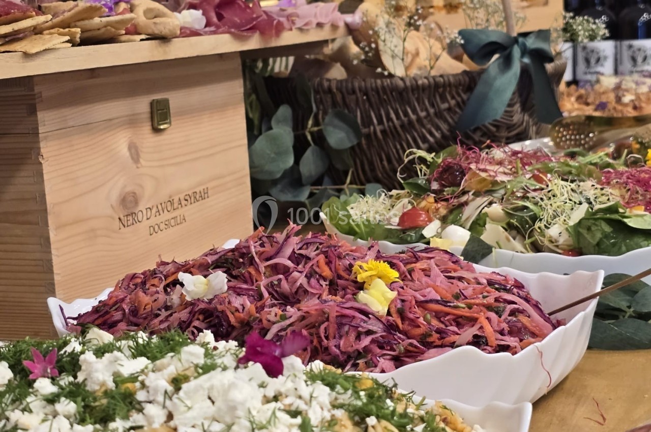 Buffet avec salades colorées, pain, charcuterie et décorations végétales sur une table en bois.