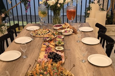 Table et deux chaises noires installées devant un mur beige avec une enseigne ’Nevian's Traiteur & Cave’.