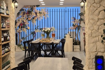 Table et deux chaises noires installées devant un mur beige avec une enseigne ’Nevian's Traiteur & Cave’.