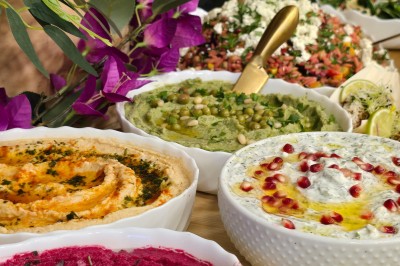 Table et deux chaises noires installées devant un mur beige avec une enseigne ’Nevian's Traiteur & Cave’.