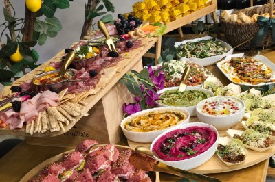 Table et deux chaises noires installées devant un mur beige avec une enseigne ’Nevian's Traiteur & Cave’.