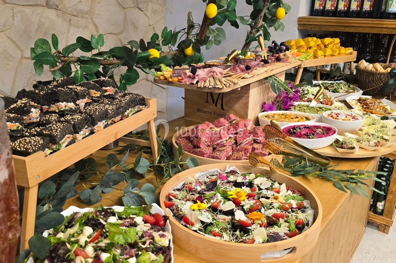 Buffet varié avec salades, charcuteries, pains et plats colorés, décoré de branches et de citrons.