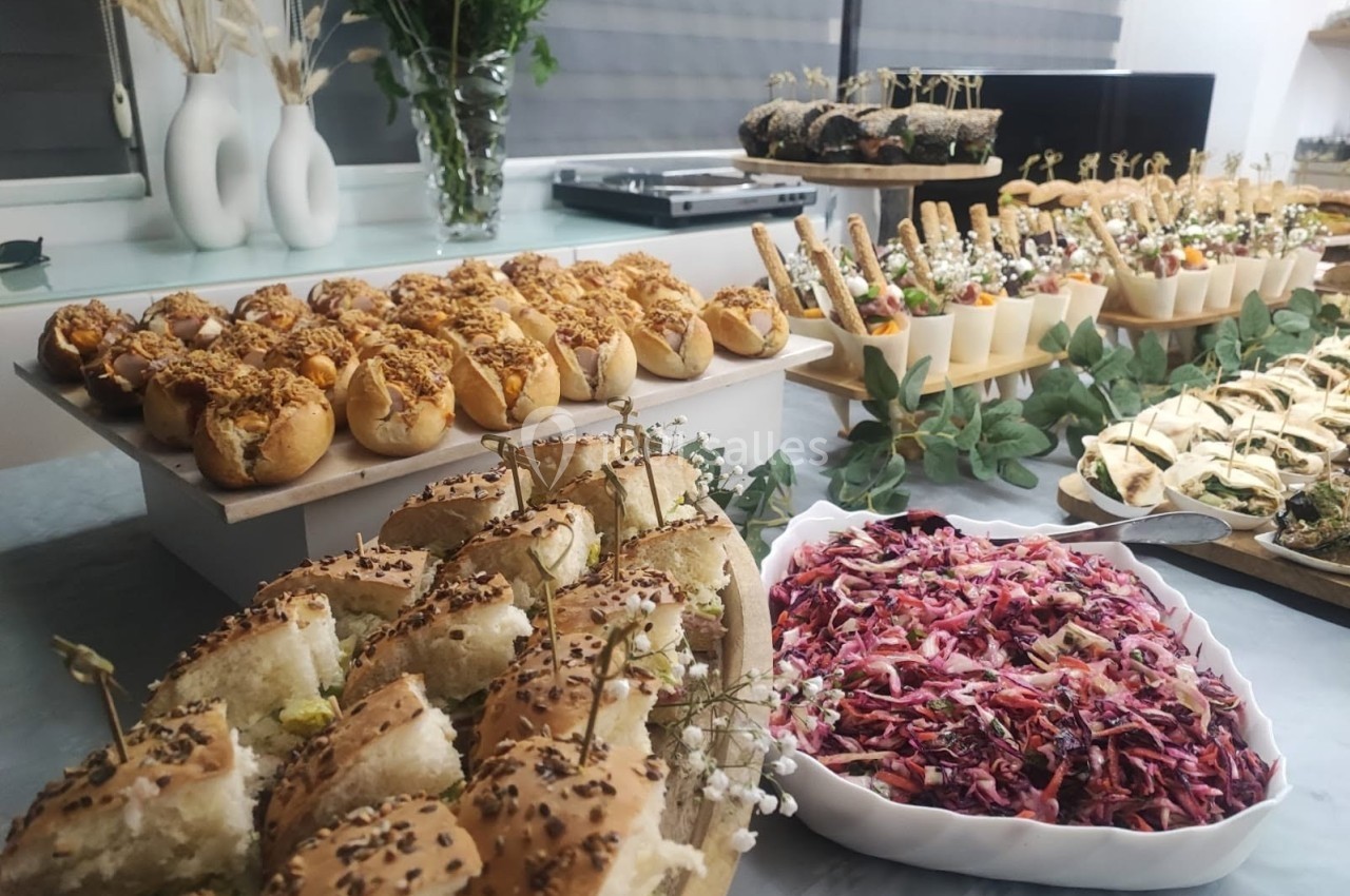Buffet varié avec pains garnis, salades colorées et amuse-bouches présentés sur une table décorée de verdure.