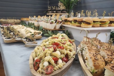 Table et deux chaises noires installées devant un mur beige avec une enseigne ’Nevian's Traiteur & Cave’.