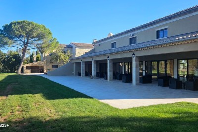 Miniature Location salle Arles (Bouches-du-Rhône) - Mas de la Grande Porcelette #3 Bâtisse en pierre avec une verrière, entourée d'une cour pavée et d'espaces verts sous un ciel dégagé.