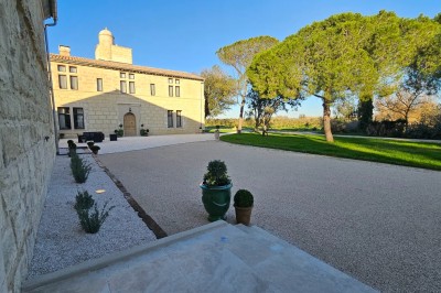 Miniature Location salle Arles (Bouches-du-Rhône) - Mas de la Grande Porcelette #1 Bâtisse en pierre avec une verrière, entourée d'une cour pavée et d'espaces verts sous un ciel dégagé.