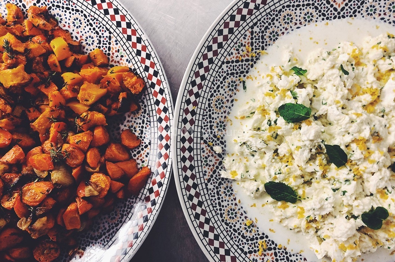 Assiette de légumes rôtis à gauche et préparation crémeuse garnie de menthe à droite, sur une table.