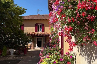 Miniature Location salle Condeissiat (Ain) - Restaurant Rolande #4 Une voiture Citroën 2CV rouge et blanche est garée devant un restaurant à façade fleurie dans un village.