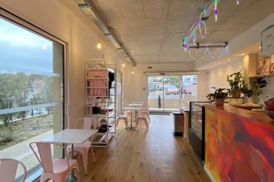 Salle vide avec parquet en bois clair, murs blancs, éclairage encastré au plafond et grande baie vitrée donnant sur l…