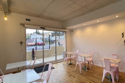 Salle vide avec parquet en bois clair, murs blancs, éclairage encastré au plafond et grande baie vitrée donnant sur l…