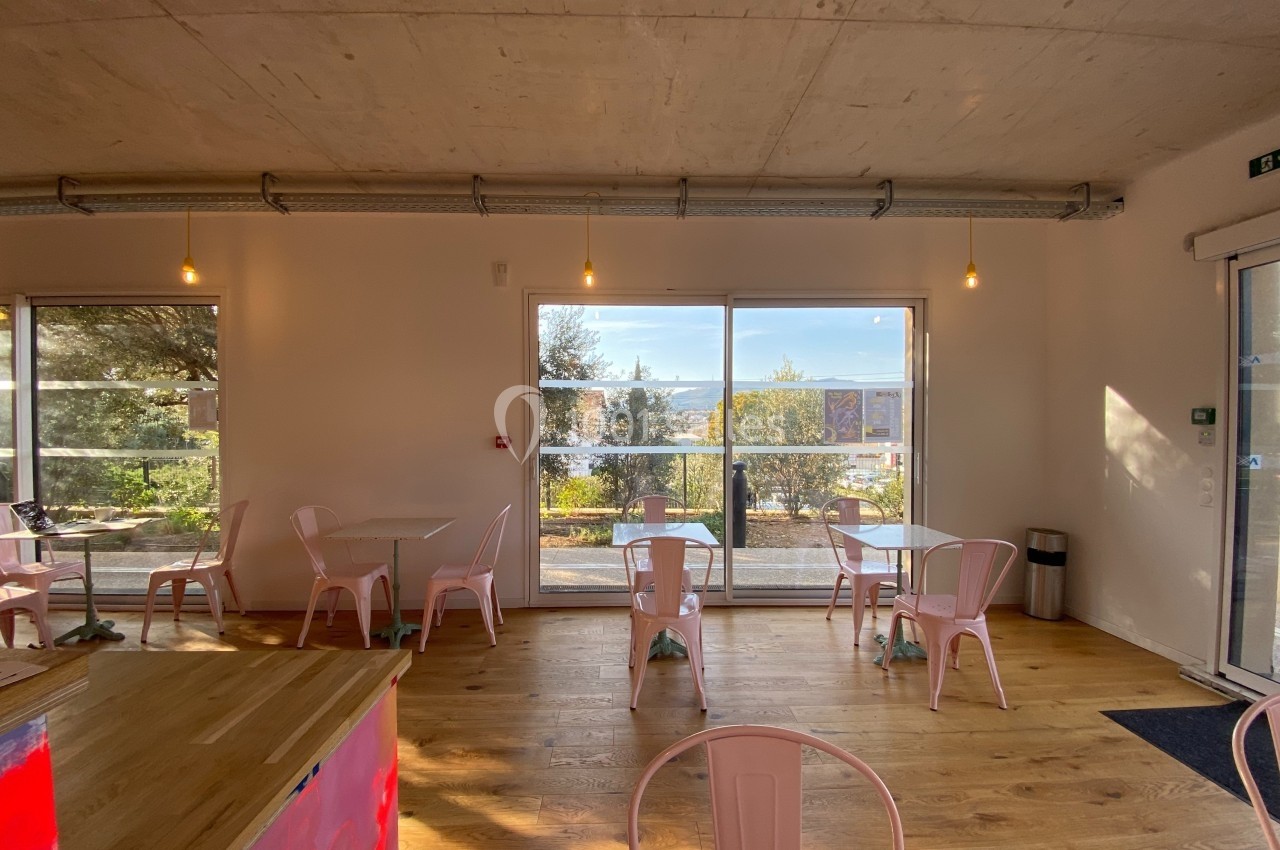 Salle lumineuse avec grandes baies vitrées donnant sur une terrasse et un paysage arboré, mobilier minimaliste.